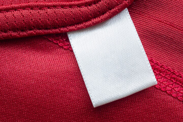 Wall Mural - White blank laundry care clothes label on red polyester sport shirt background