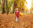 © okostia - Portrait of happy joyful running child girl on fallen yellow autumn foliage in autumn city forest park in rays of sunset light