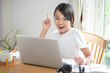 © OHishi_Foto - smiling asian girl using  laptop and happy to learn online at home and wearing white t-shirt
