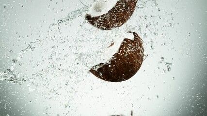 Fototapete - Super slow motion of coconut pieces flying in the air with water splashes. Filmed on high speed cinema camera, 1000 fps.