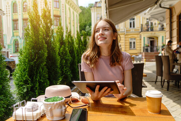 young woman using tablet pc in a cafe on a summer terrace