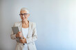 © Dragana Gordic - Studio portrait of a confident mature woman posing against a gray background with laptop. Senior business woman standing against grey background with copy space.