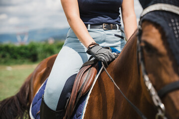 Beautiful young woman on a summer day rides with his horse in the grass field - Millennial has fun with his animal friend in a riding center