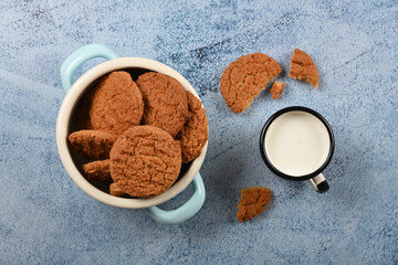 Wall Mural - Oatmeal cookies and pannikin of milk on blue table