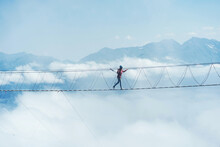 A Person Walks On A Suspended Rope Bridge In The Clouds. Extreme Attraction.