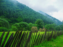Traditional Haystacks In A Clouded Hillside Meadow.