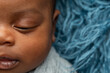 © Ursula Page - Close-up sleepy swaddled African-American newborn baby boy laying on a blue rug in a basket with copy space
