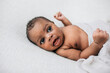 © Ursula Page - Happy, awake and cute African-American newborn baby boy laying on a cream-colored blanket