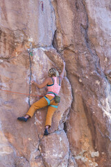 Wall Mural - A strong woman climbs a beautiful orange rock.