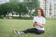 © bisonov - Young happy woman talking on cell phone sitting on grass