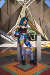 Canvas Print - Vertical shot of a young lady with blue hair and tattoos wearing colorful clothing holding a ball