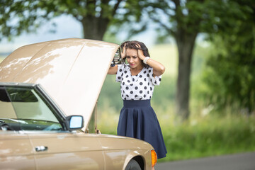 Good looking girl holding her head in hands from desperation after engine failure stopped the car in the nature