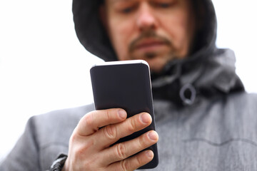 Married man in hood holds and looks at smartphone