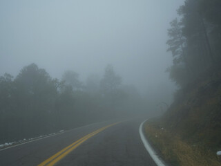 A curvy mountain road leading into heavy fog