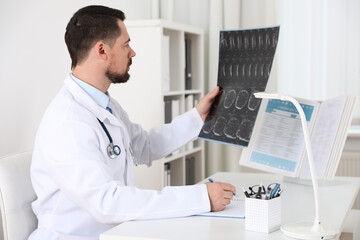 Poster - Orthopedist examining X-ray picture at desk in clinic