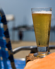 Sticker - Vertical selective focus shot of a glass of cold beer at a beach