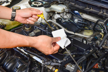 A professional mechanic is holding the oil dipstick check the oil level in car engine