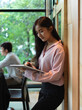 © bongkarn - Portrait of businesswoman working with digital tablet while standing in meeting room