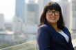 © Ranta Images - Happy young beautiful overweight Asian businesswoman against view of the city