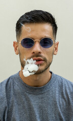 Canvas Print - Vertical shot of cigarette smoke getting out of a young caucasian male in sunglasses