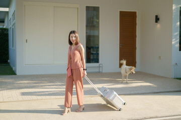 Asian woman moving in a new house.  pull luggage and walk to home door entrance.