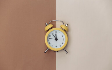 Yellow retro alarm clock on brown beige background. Top view. Minimalism