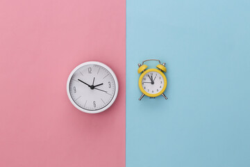 Clock and alarm clock on pink blue pastel background. Top view. Flat lay