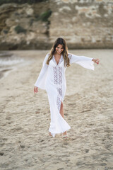 Canvas Print - Vertical shot a young European female wearing a white dress standing on the seashore