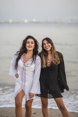 Portrait of two sexy females wearing black and white dresses while enjoying the beach