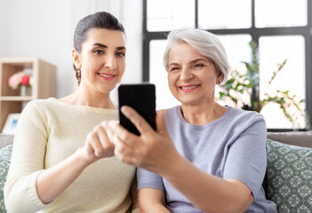 Sticker - family, generation and technology concept - happy smiling senior mother and adult daughter with smartphone at home