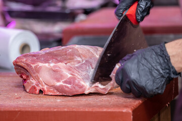 Wall Mural - Closeup shot of a butcher's hands slicing up raw meat