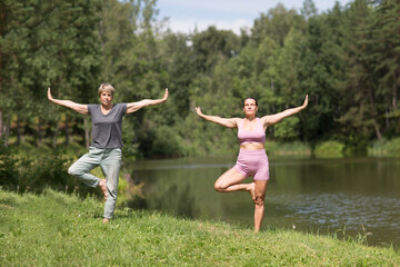 Wall Mural - elderly woman doing in yoga and stretching with an instructor in nature. Healthy lifestyle concept. outdoor activities. 