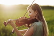 © Maksim Selin - Romantic woman with loose hair playing the violin. Sunset light in nature