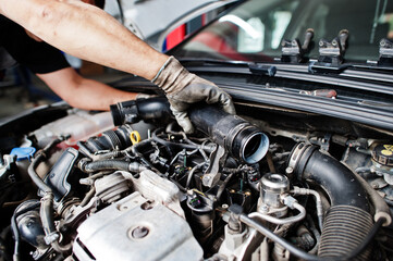 Car repair and maintenance theme. Mechanic in uniform working in auto service, checking engine.