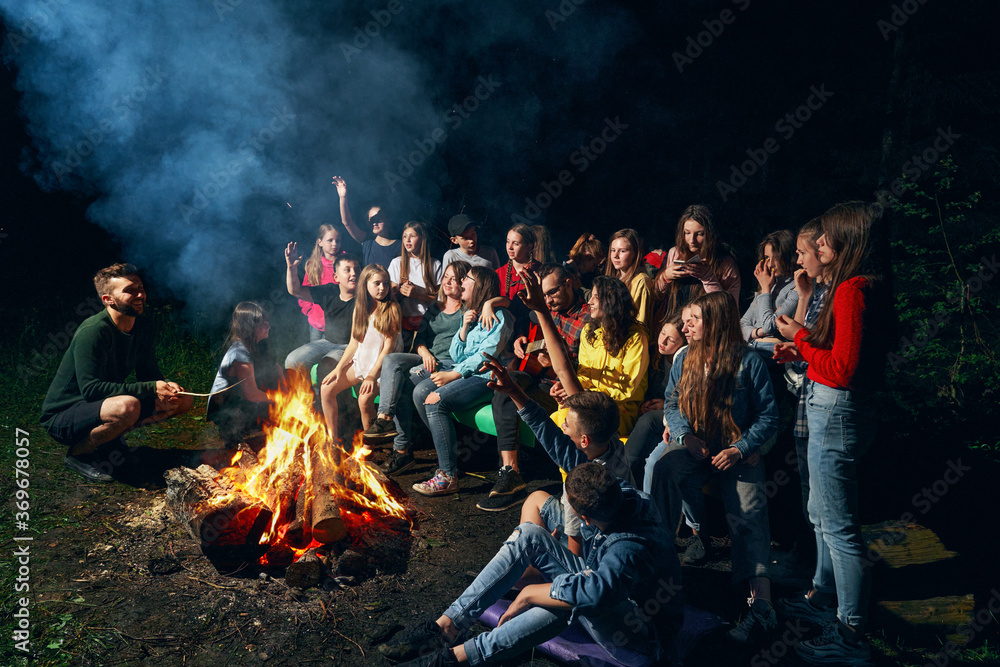 Children singing near camp fire. - obrazy, fototapety, plakaty 