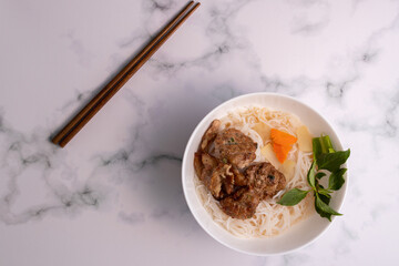 Sticker - High angle shot of an Asian dish with noodles and meat, with chopsticks on a marble surface