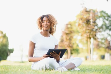 Outdoor portrait of a smiling teenage black girl using a tactile tablet - African people