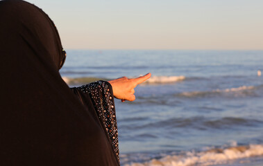 Wall Mural - Arab woman with veil on her head pointing to a distant point in