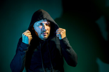 A male intruder with a hood on his head poses on a dark  background