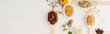 panoramic shot of herbs in spoons and flowers on white wooden background, naturopathy concept