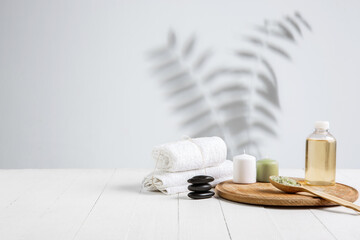 Beautiful spa composition on massage table in wellness center, copyspace. Accessories for relaxing treatments and personal care. Towels, oils, serum, sea salts and scrubs. Decorative candles