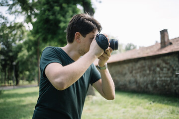 Close-up view of photographer looking through camera viewfinder. Portrait of man holding DSLR camera and looking through camera viewfinder.