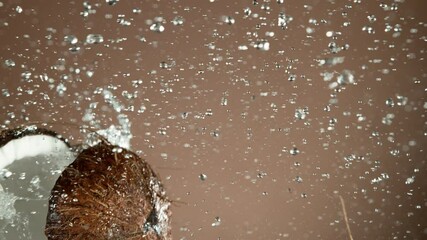 Fototapete - Super slow motion of coconut pieces flying in the air with water splashes. Filmed on high speed cinema camera, 1000 fps.