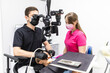 © F8  \ Suport Ukraine - Happy girl in a dental clinic. Dentist in a gray uniform and latex gloves looks in a dental microscope while examining her teeth with a help of a dental mirror and his assistant uses an air polisher.