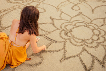 woman drawing the big mandala at sand in empty beach.concept of femininity and independence