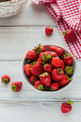 Wall Mural - Fresh strawberries on ceramic bowl top view. Healthy food on white wooden table. Delicious, sweet, juicy and ripe berry background with copyspace for text