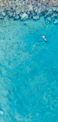 Wall Mural - An aerial view of the beautiful Mediterranean Sea and a swimmer, where you can see   the cracked rocky textured underwater corals and the clean turquoise water of Protaras, Cyprus, 