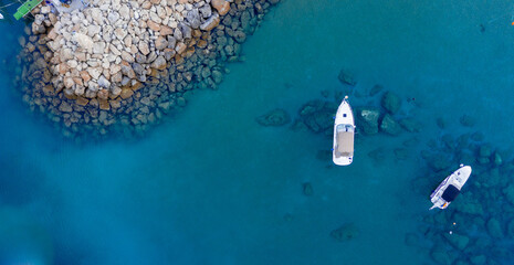 Wall Mural - Aerial shot of boats on a crystal clear sea surrounded by rocks in Protaras, Cyprus