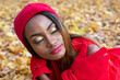 © photosaint - Beautiful African girl in red clothes resting in autumn leaves