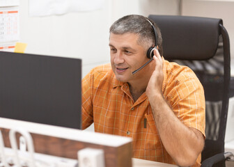 Online working. Smiley man with headset having online conversation.